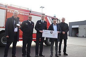 Vertreter der Stadt Euskirchen mit Feuerwehrleuten vor einem Feuerwehrfahrzeug an der Feuerwache in Euskirchen.